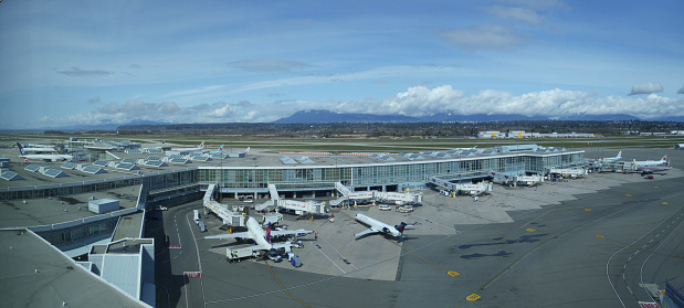 VANCOUVER INTERNATIONAL AIRPORT, CANADA, MARCH 2018: AERIAL: Large white Delta and Air Canada airplanes getting ready for boarding at Vancouver International Airport. Aircrafts surrounding airport.