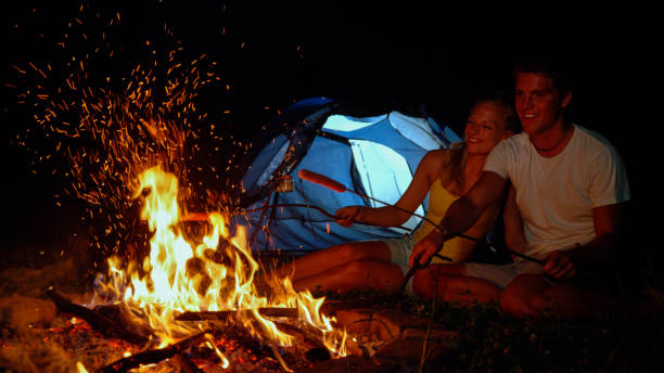 istock CLOSE UP: Happy camper striking fire while roasting sausages with girlfriend. 1185003028