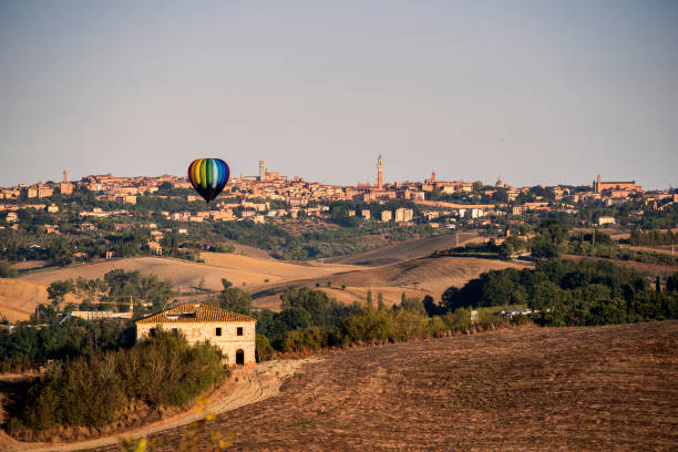 Panorama of Siena at dawn with hot air balloon Panorama of city of Siena at dawn with hot air balloon torre del mangia stock pictures, royalty-free photos & images