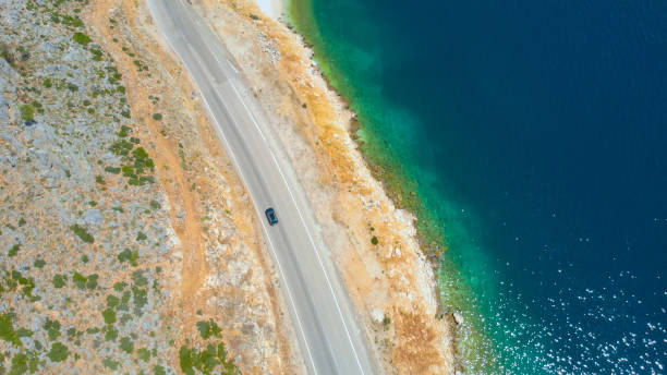 istock AERIAL: Deep blue ocean glistens while the car cruises down the scenic road. 1185007062