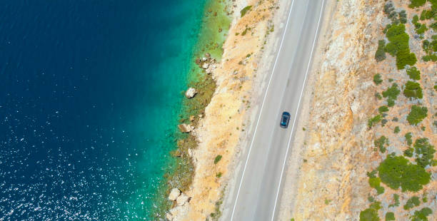 istock TOP DOWN: Car cruises down the empty road leading along beautiful rocky beach. 1185007468