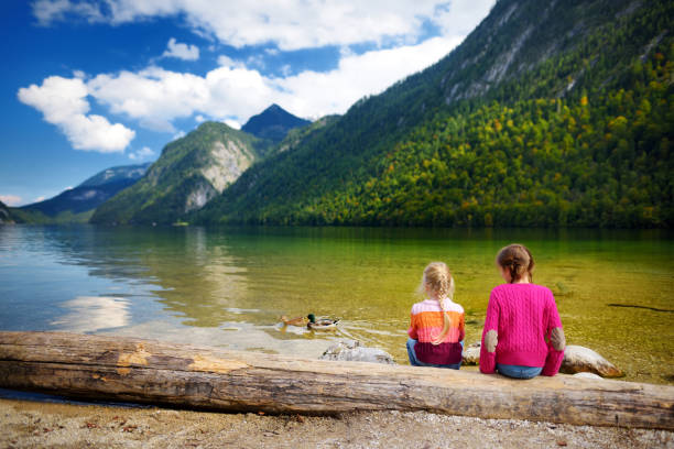 две милые сестры наслаждаются видом на глубокие зеленые воды кенигсе, известного как самое глубокое и чистое озеро германии, расположенное - bayern стоковые фото и изображения