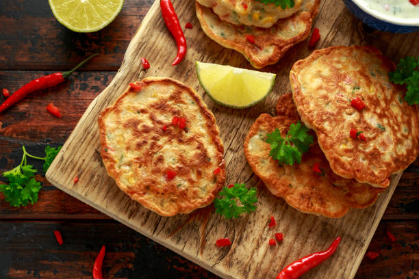 istock Corn fritters, pancake with dip white sauce, lime and chilli on wooden board 1185013618