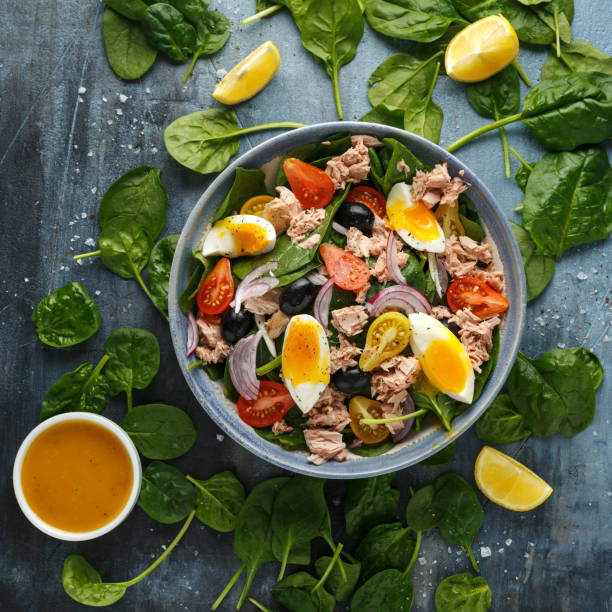 istock Protein packed tuna and soft, runny egg salad with pear shaped cherry tomatoes, black olives and spinach 1185013706
