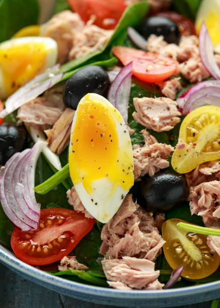 istock Protein packed tuna and soft, runny egg salad with pear shaped cherry tomatoes, black olives and spinach 1185014523