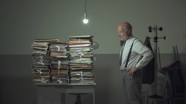 istock Business executive staring at the stacked paperwork on his desk 1185015835