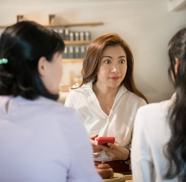 istock Women having tea in Tea Room, one using mobile phone 1185016004
