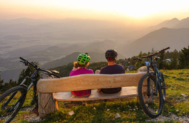 istock CLOSE UP: Unrecognizable bicycle riders sit and observe the sunset from a bench 1185016034