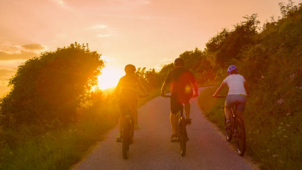 istock LENS FLARE: Fit friends enjoy a bicycle journey on an idyllic summer evening. 1185018103