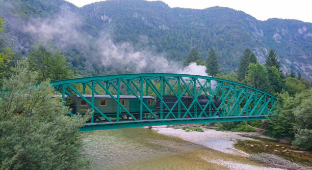 locomotiva aposentada atravessa o rio que atravessa as montanhas verdes. - bohinj - fotografias e filmes do acervo