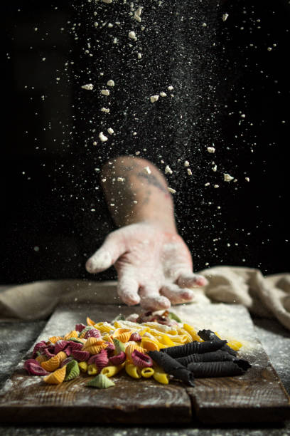 istock man's hand throws flour over a wooden table with pasta 1185019036