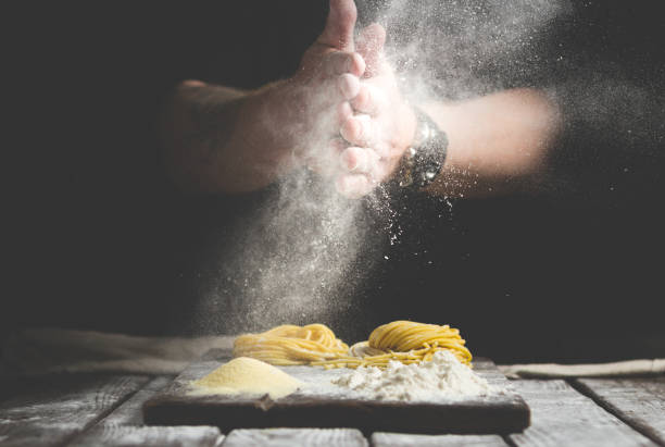 istock hands in flour, make homemade pasta on a table on black background 1185019063