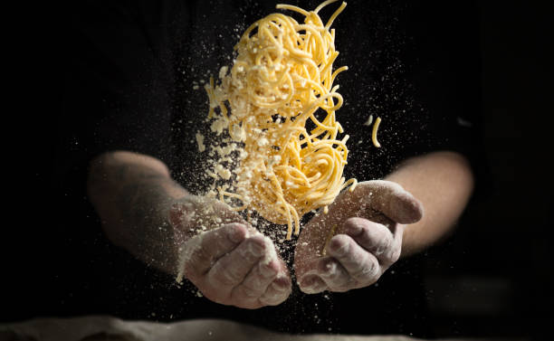 istock close hand make pasta toss f on a black background before cooking the dish 1185019128
