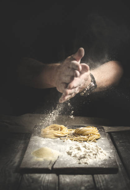 istock hands in flour, make homemade pasta on a table on black background 1185019149