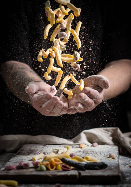 istock close hand make pasta toss f on a black background before cooking the dish 1185019703