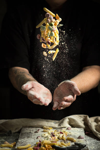 close hand make pasta toss f on a black background before cooking the dish close hand make pasta toss f on a black background before cooking the dish flour mess stock pictures, royalty-free photos & images