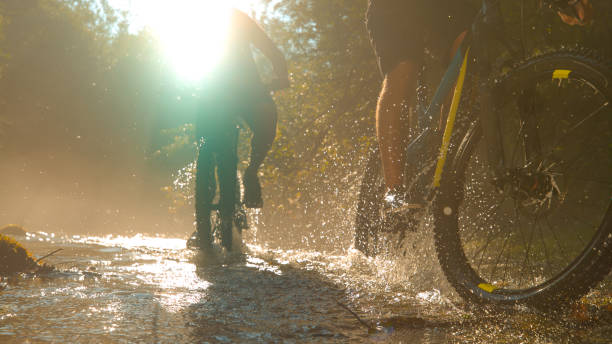 istock SUN FLARE: Blinding sunbeams illuminate the river as two men cycle across river. 1185021157