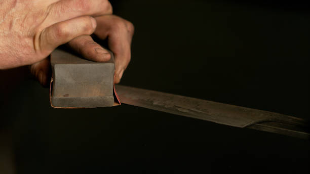 istock CLOSE UP: Male craftsman sharpening and working on a traditional knife blade. 1185021438