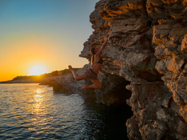 istock SUN FLARE: Strong girl climbs a challenging cliff on a sunny summer evening. 1185022286