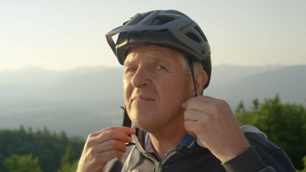 istock PORTRAIT: Older man puts on a helmet before a bicycle ride on a sunny evening. 1185022532
