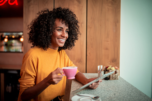 Young African-American woman drinks coffee at the coffee shop.