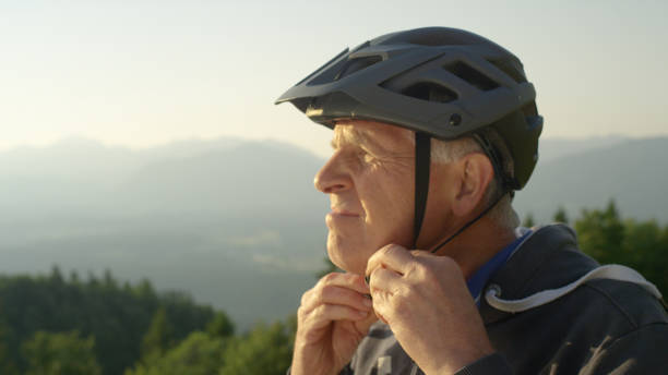 istock CLOSE UP: Focused senior man straps up his helmet before an evening bicycle ride 1185024294