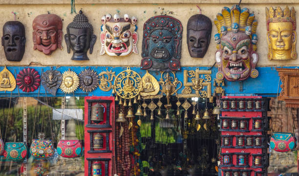 CLOSE UP: Traditional wooden buddhist masks hang on the wall of a souvenir shop. CLOSE UP: Traditional wooden buddhist masks hang on the wall of a souvenir shop in Swayambhunath temple complex in Kathmandu. Intriguing hand carved masks and golden bells up for sale for tourists. carving craft product stock pictures, royalty-free photos & images