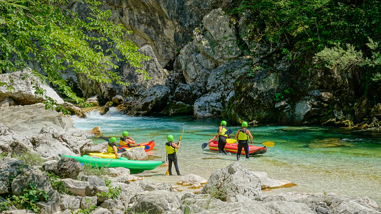A group of active tourists prepare their canoes for a rafting trip down the gorgeous Soca river. Travelers prepare their equipment before a kayaking trip around the picturesque Soca river valley.