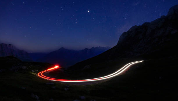 istock TIMELAPSE: Car lights create a blurry trail leading through mountains at night 1185024953
