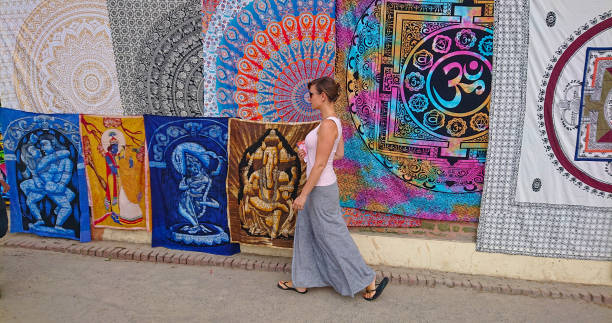 female traveler walking along the sidewalk with blankets on display for tourists - nepal bazaar kathmandu textile imagens e fotografias de stock