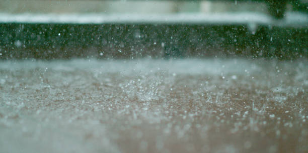 istock MACRO, DOF: Raindrops fall into a small puddle forming on the floor of a balcony 1185025423