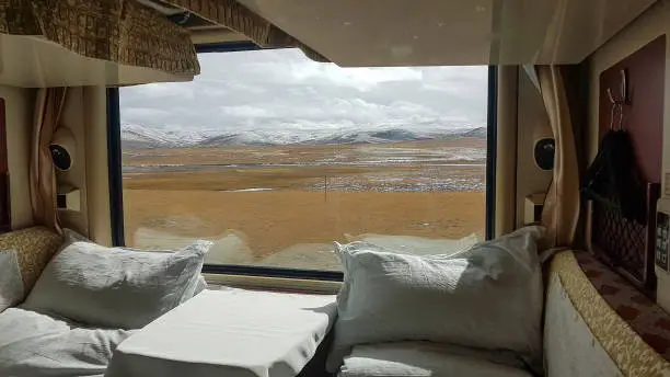 CLOSE UP: Picturesque view of the snowy Tibetan landscape from a comfortable sleeper train. Two beds in a luxury cabin lay empty as the Trans-Himalayan overnight train crosses the Chinese countryside.
