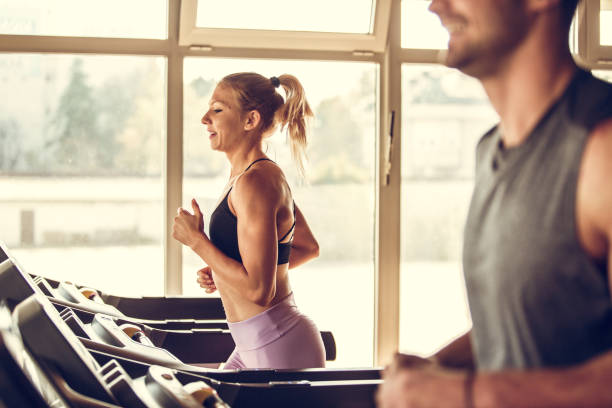 istock Smiling athletic young woman running on a treadmill 1185030269