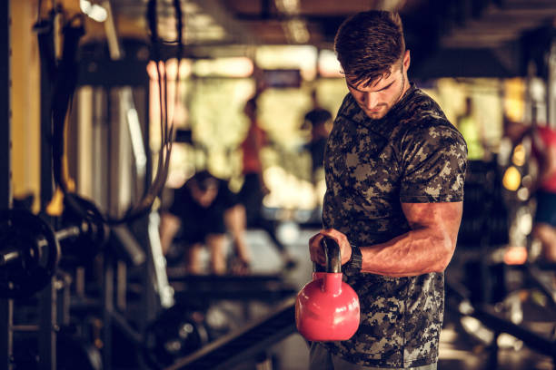 istock Athletic young man doing bicep curls with kettle bells 1185031334