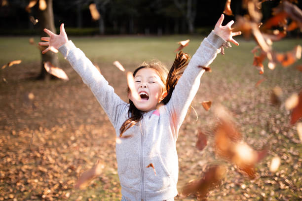 istock Girl playing with fallen leaves 1185032705