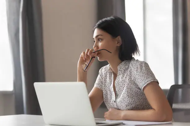 Photo of Thoughtful anxious asian business woman looking away thinking solving problem