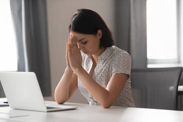 skoncentrowana azjatycka bizneswoman wkłada ręce w modlitwę w pracy - begging pleading praying business zdjęcia i obrazy z banku zdjęć