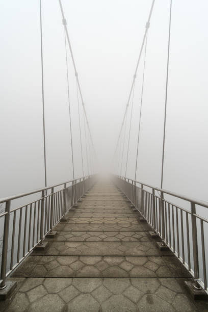 istock Hanging bridge vanishing in fog 1185051098