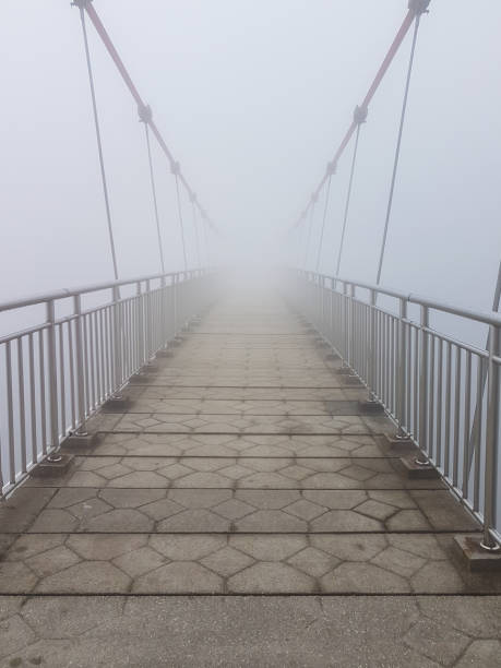 istock Hanging bridge vanishing in fog 1185051183