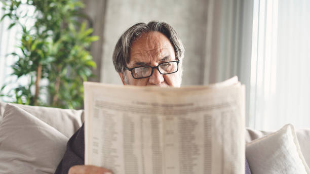 istock Senior man reading newspaper at home 1185054334
