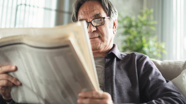 istock Senior man reading newspaper at home 1185054385