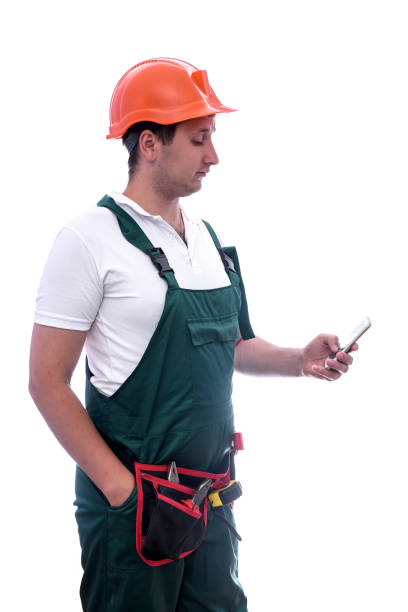 istock Workman in coverall holding mobile phone isolated on white 1185062603