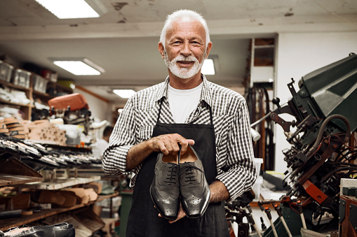 Shoe maker in workshop showing shoes