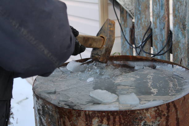 istock a man breaks the ice with a hammer in a barrel 1185067337
