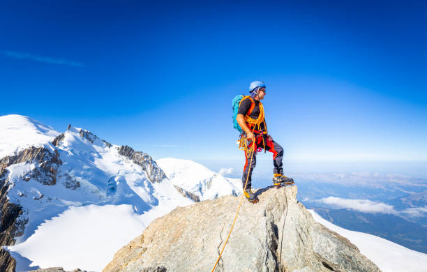 Alpinist guy mountaineer man standing posing Mont Blanc du Tacul snow mountain summit. Chamonix valley view beautiful landscape, Europe France Alps range tourism.