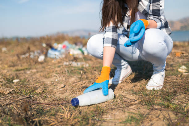 istock Female volunteer picking up plastic trash outdoors. Environment and save the earth concept. 1185069065