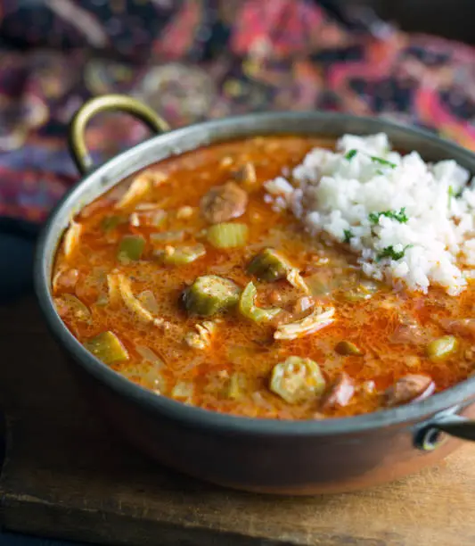 Close view of a small pot of chicken and sausage gumbo with a scoop of rice.