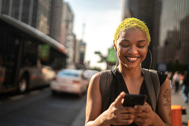 istock Young woman walking and using smartphone at city 1185076455