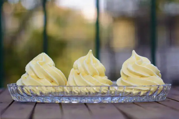 Three yellowish meringues in a glass cake plate.
