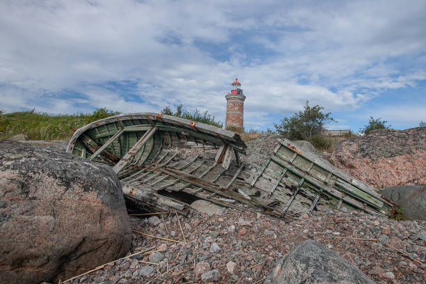 istock Lighthouse and old boat in the Baltic Sea. Shore, evening light, sunset, clouds and architecture concept. Mohni, small island in Estonia, Europe. 1185078982